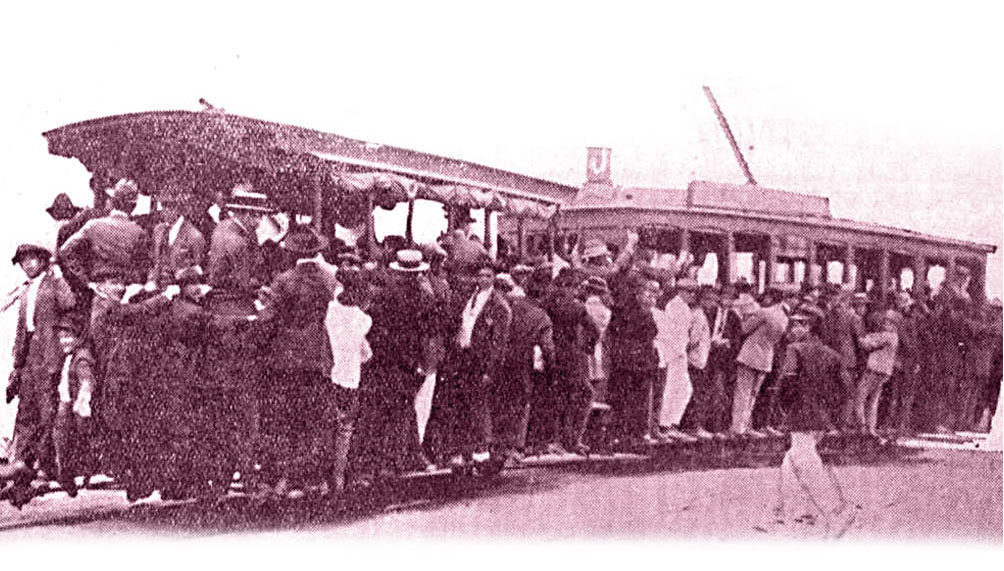 Fotografia de um bonde composto em abarrotado de passageiros, quase todos homens, usada em anúncio da Companhia Carris de Porto Alegre na Revista do Município, Ano 1930, Ed00022-4, p4. Hemeroteca Digital da Biblioteca Nacional.